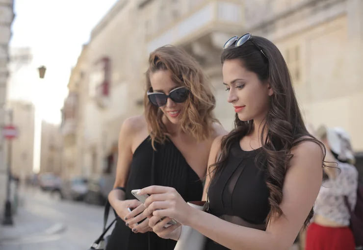 Two people on a city street looking something up on a phone
