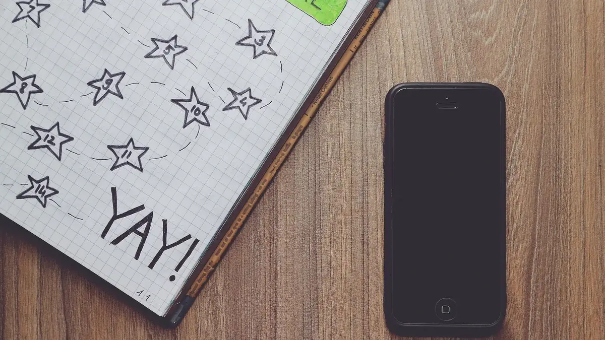 A notebook covered in hand drawn stars next to a phone on a desk
